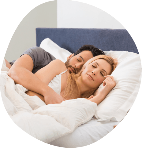 Smiling man and woman cuddling while they sleep