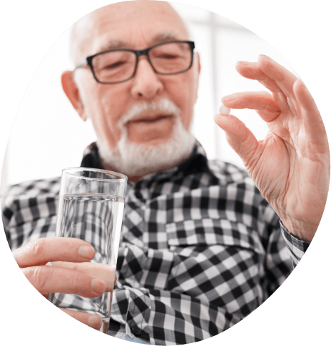 Senior man holding a pill and glass of water
