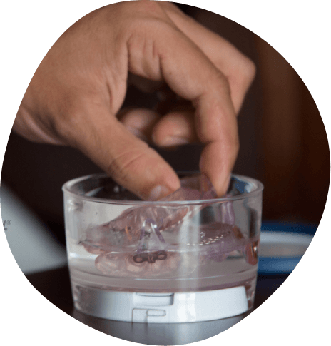 Person washing their oral appliance in a glass of water