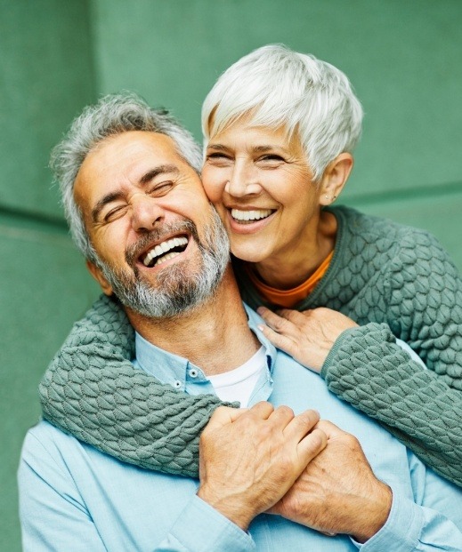 Older man and woman laughing and holding each other