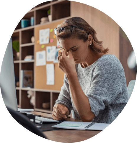 Tired businesswoman pinching the bridge of her nose while sitting at desk