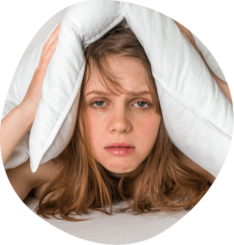 Tired woman in bed covering the top of her head with her pillow