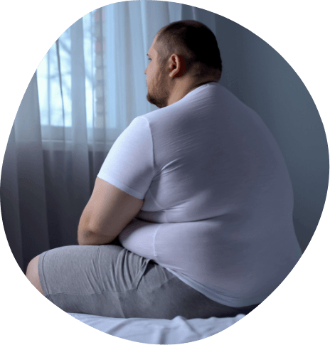 Chubby man sitting on the edge of his bed