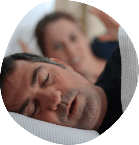 Woman looking at snoring man next to her in bed