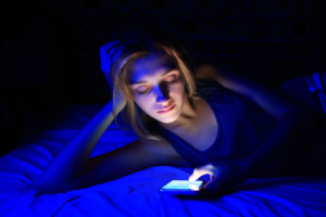 a woman using her cell phone while in bed