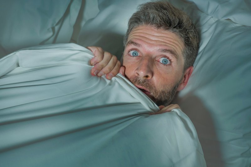 man appearing frightened while in bed