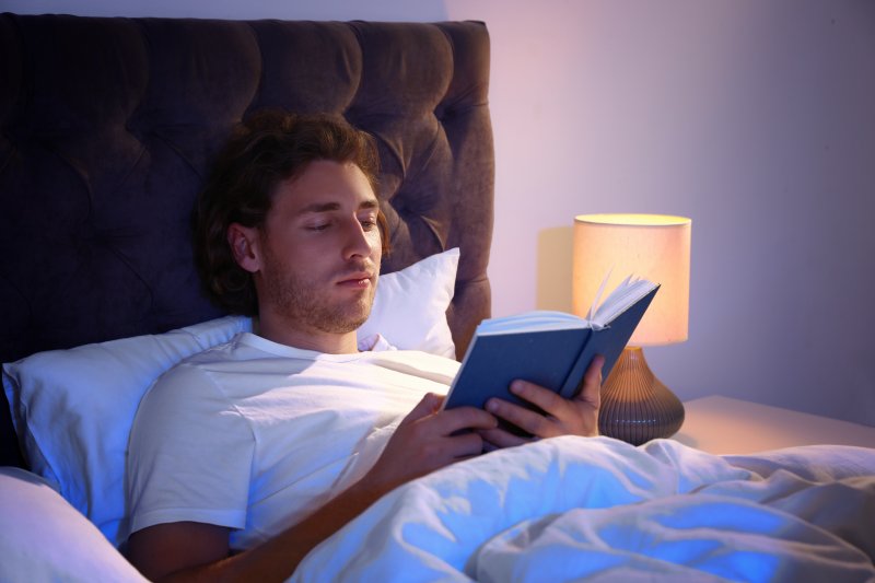 man lying in bed reading a book