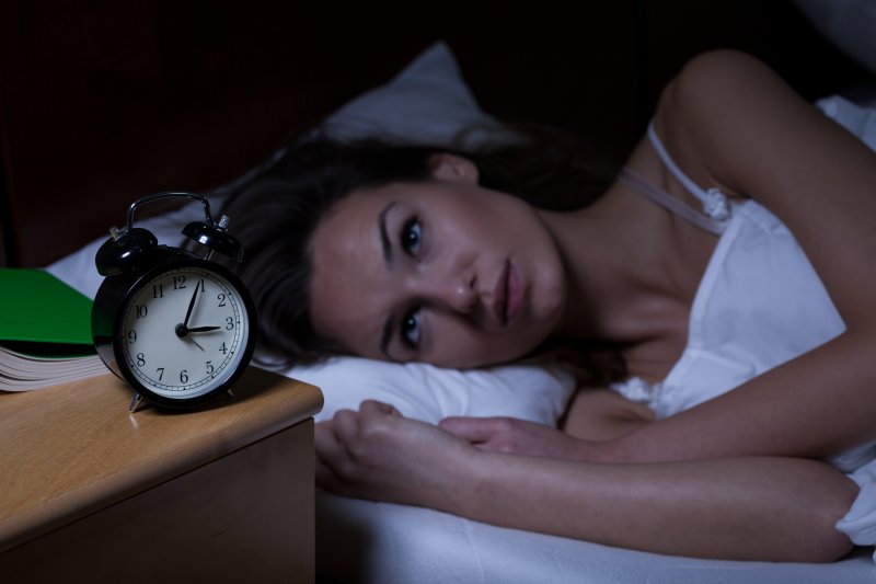 woman lying in bed looking at the clock